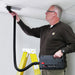 Technician carrying an Atrix VACEXP-04 and using its hose to clean an overhead grille