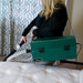 Operator using the Atrix VACOMEGASIPM green vacuum and clear hose beside a mattress