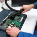 Technician using an Atrix VACOSE110 hose and brush around an exposed circuit board