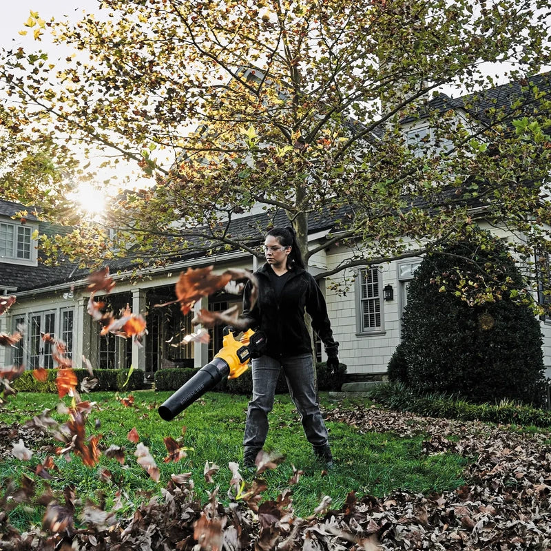 DEWALT DCBL772X1 cordless blower clearing fallen leaves in a yard