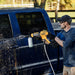 DEWALT DCPW550P1 battery pressure washer cleaning a car exterior