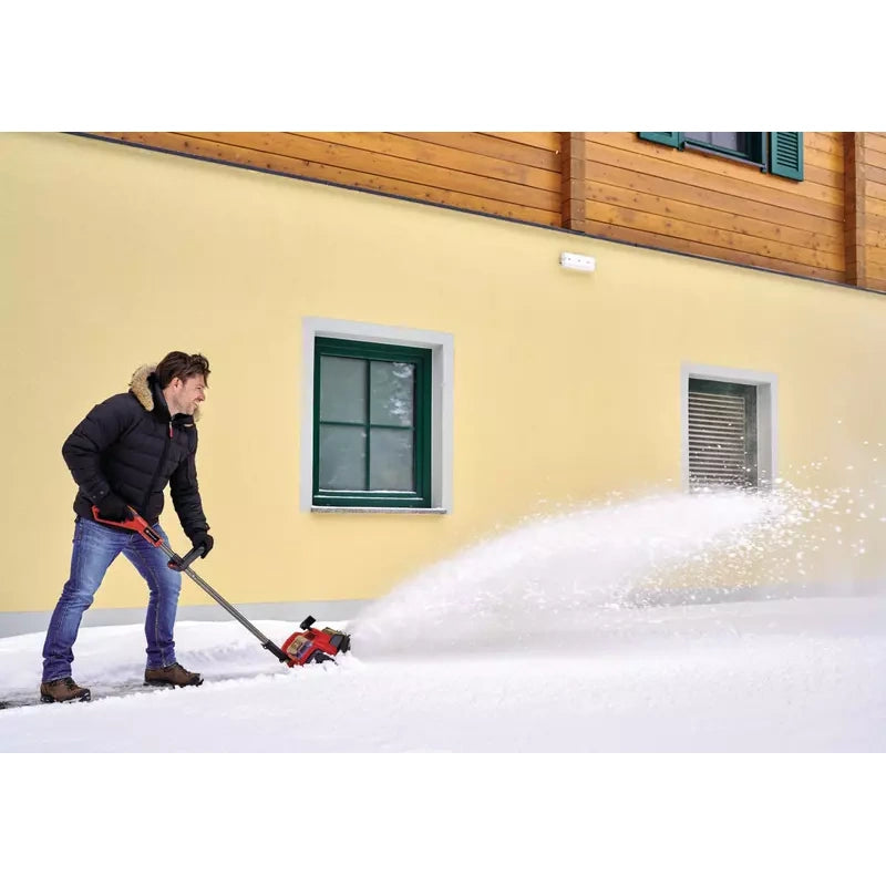 Einhell 36V cordless snow shovel clearing snow beside a building