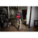 Worker wearing a Milwaukee 0895-20 backpack vacuum while cleaning a floor