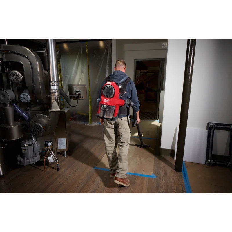 Worker wearing a Milwaukee 0895-20 backpack vacuum while cleaning a floor