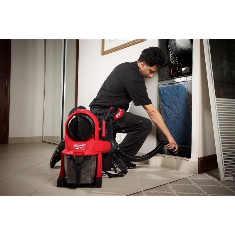 Worker using a Milwaukee 0895-20 vacuum hose to clean inside an open recess