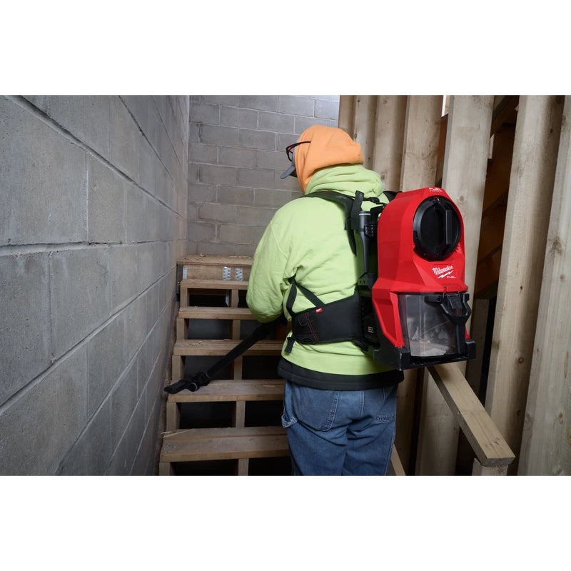 Worker wearing a Milwaukee 0895-20 backpack vacuum while cleaning a wooden staircase